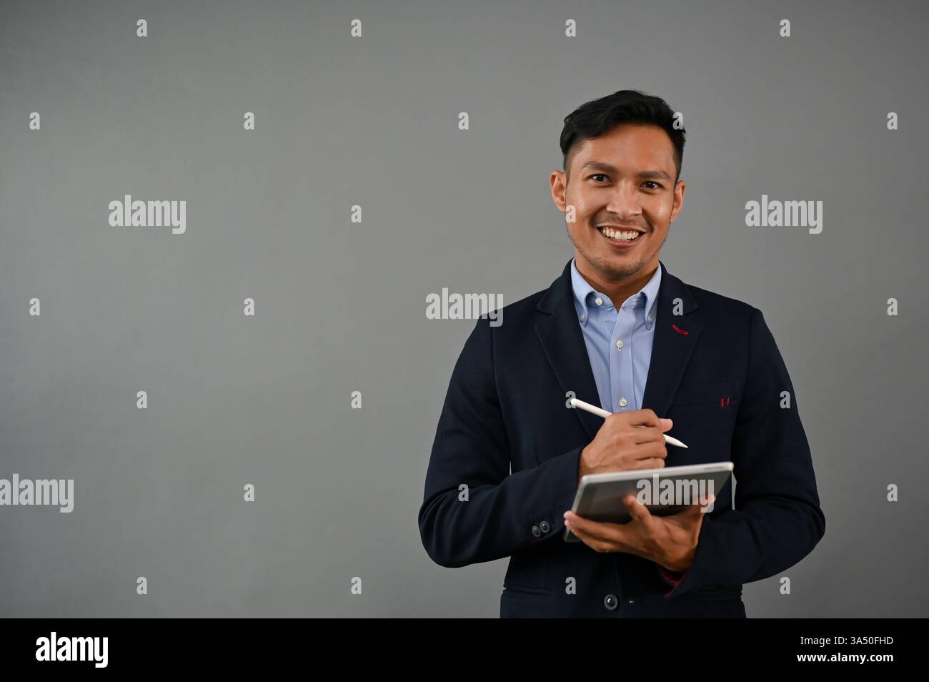 Das Porträt eines professionellen und erfolgreichen asiatischen Millennials im formellen Business-Anzug steht auf einem isolierten grauen Hintergrund mit seinem digitalen Hintergrund Stockfoto