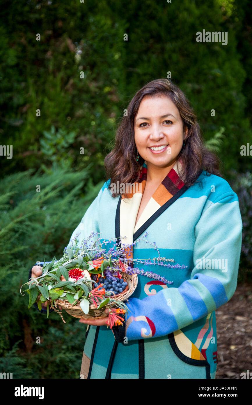 Ponca Stammesmitglied und Kräuterist präsentiert einen Korb mit natürlichen Pflanzen und Früchten, die in traditionellen medizinischen Lotionen verwendet werden. Ideal für Themen zu einheimischer Kräutermedizin, traditioneller Hautpflege und pflanzlichen Inhaltsstoffen. Sie hebt das kulturelle Erbe und das einheimische Know-how im Bereich Naturheilmittel hervor. Stockfoto