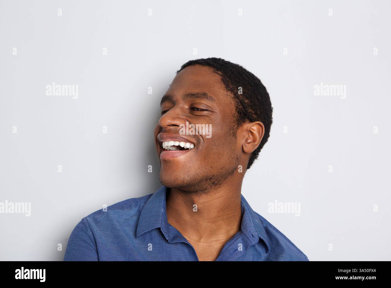 Horizontales Nahporträt eines lachenden Afrikaners vor weißem Hintergrund. Ein lebendiger, fröhlicher Headshot, der sich für Lifestyle, Gesundheit und positive Botschaften eignet. Stockfoto