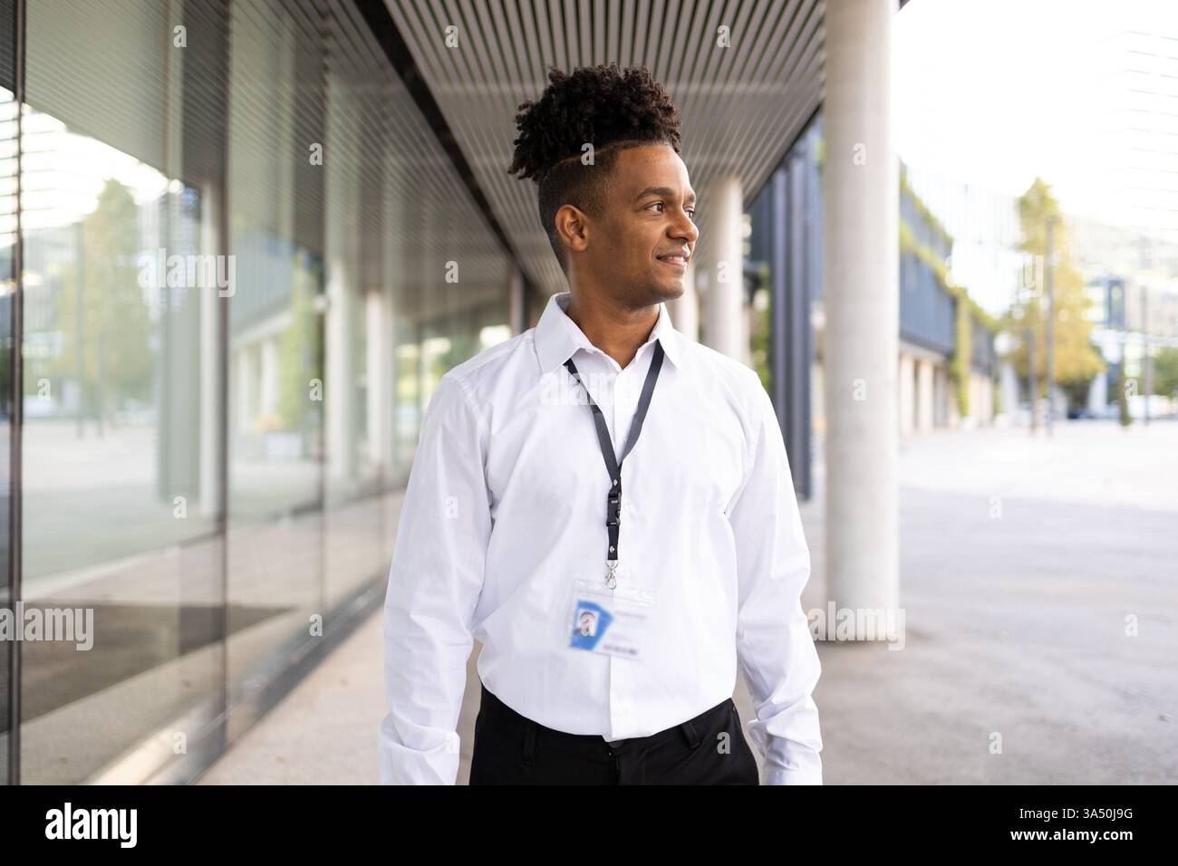Selbstbewusster afroamerikanischer männlicher Arbeiter in formeller Kleidung mit verdrehten Dreadlocks steht an einem modernen Gebäude in einer Stadtstraße. Das professionelle Porträt der Stadt vermittelt Ehrgeiz, Stil und Karrierefreiheit. Geeignet für Unternehmensprofile, Personalbeschaffung und städtische Geschäftsthemen. Stockfoto