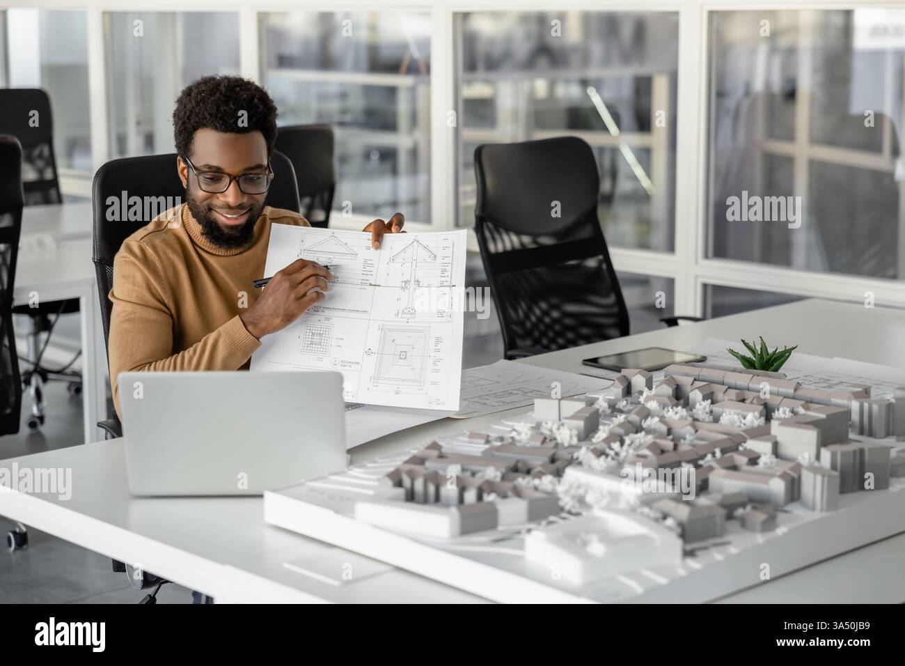 Architekt demonstriert sein Projekt in einem Online-Tutorial und sieht zufrieden aus. Die Szene eignet sich ideal für Artikel über Online-Lernen in Architektur, digitale Präsentation und Remote Collaboration. Stockfoto