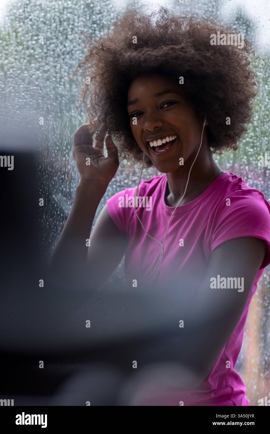 Porträt einer jungen Afro-Amerikanerin in einem Fitnessstudio während einer Trainingspause. Sie schlürft Wasser und atmet auf und zeigt Fitness und sportlichen Lebensstil. Ein vielseitiges Fitness-Image für Wellness-, Trainings- und Sportkampagnen. Stockfoto