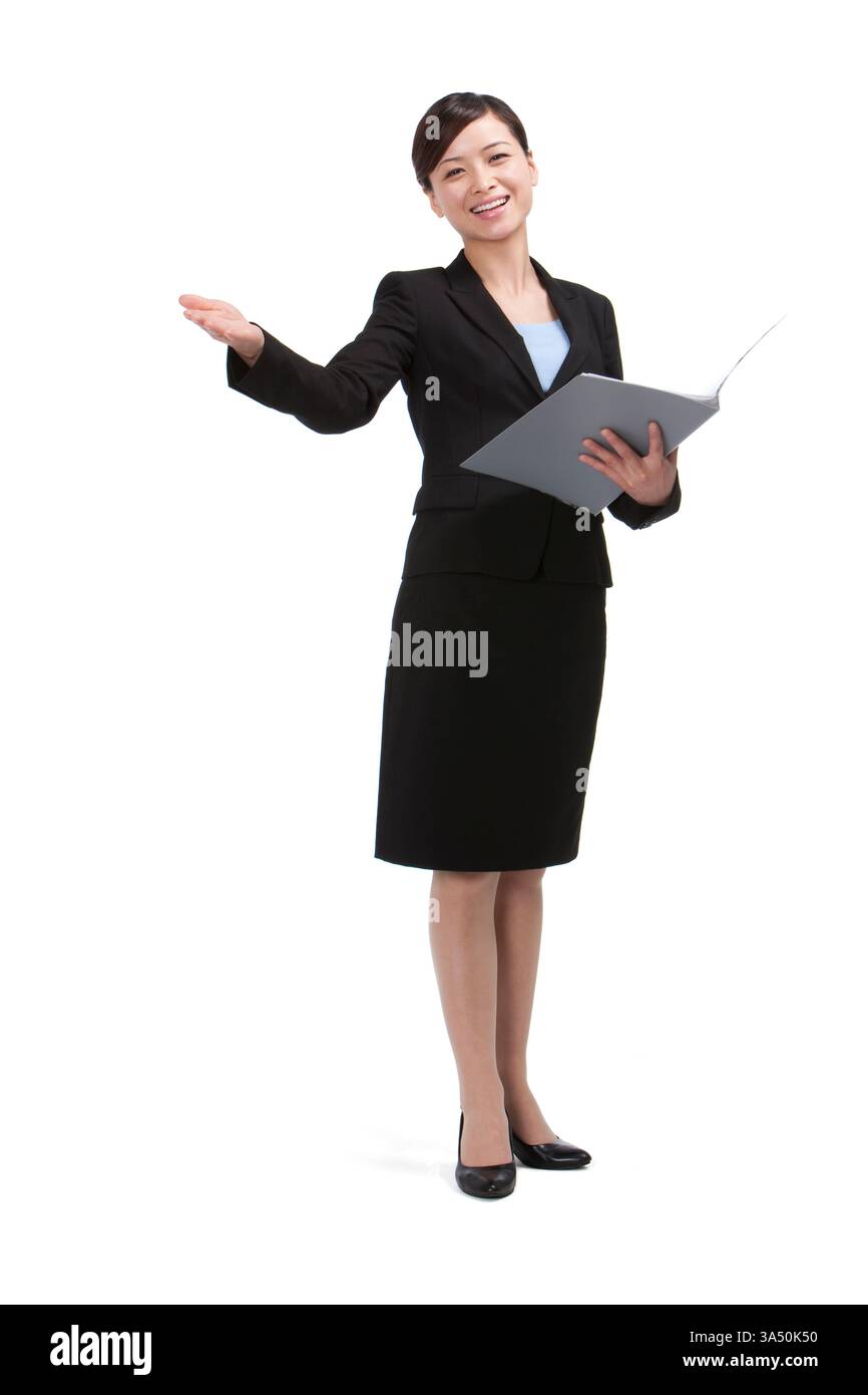Porträt einer lächelnden chinesischen Geschäftsfrau in einem Atelier, die ihren Arm hebt, während sie einen Ordner hält. Vermittelt Vertrauen, Führungsstärke und Energie, ideal für Unternehmenskommunikation und Erfolgsbotschaften. Geeignet für Themen wie Präsentation, berufliche Entwicklung und positive Geschäftsbilder. Stockfoto