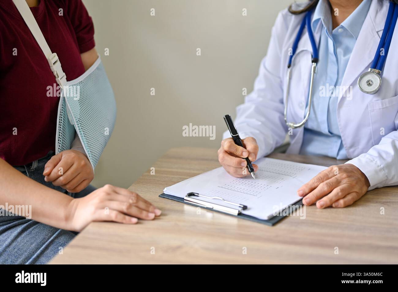 Nahaufnahme einer Patientin mit gebrochenem Arm bei einer orthopädischen Untersuchung im Krankenhaus. Die Szene konzentriert sich auf Diagnose, Pflege und Heilung von Verletzungen. Ideal für medizinische und medizinische Einrichtungen, mit orthopädischen Dienstleistungen. Stockfoto
