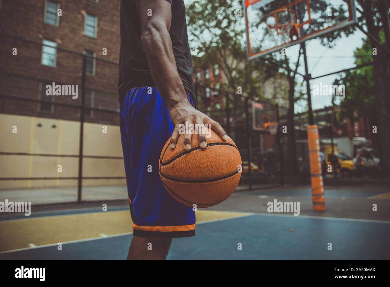 Basketballspieler trainiert auf einem Platz in New York City und fängt die Energie des städtischen Sports ein. Die Szene betont Engagement, Leichtathletik und Straßenbasketball. Stockfoto