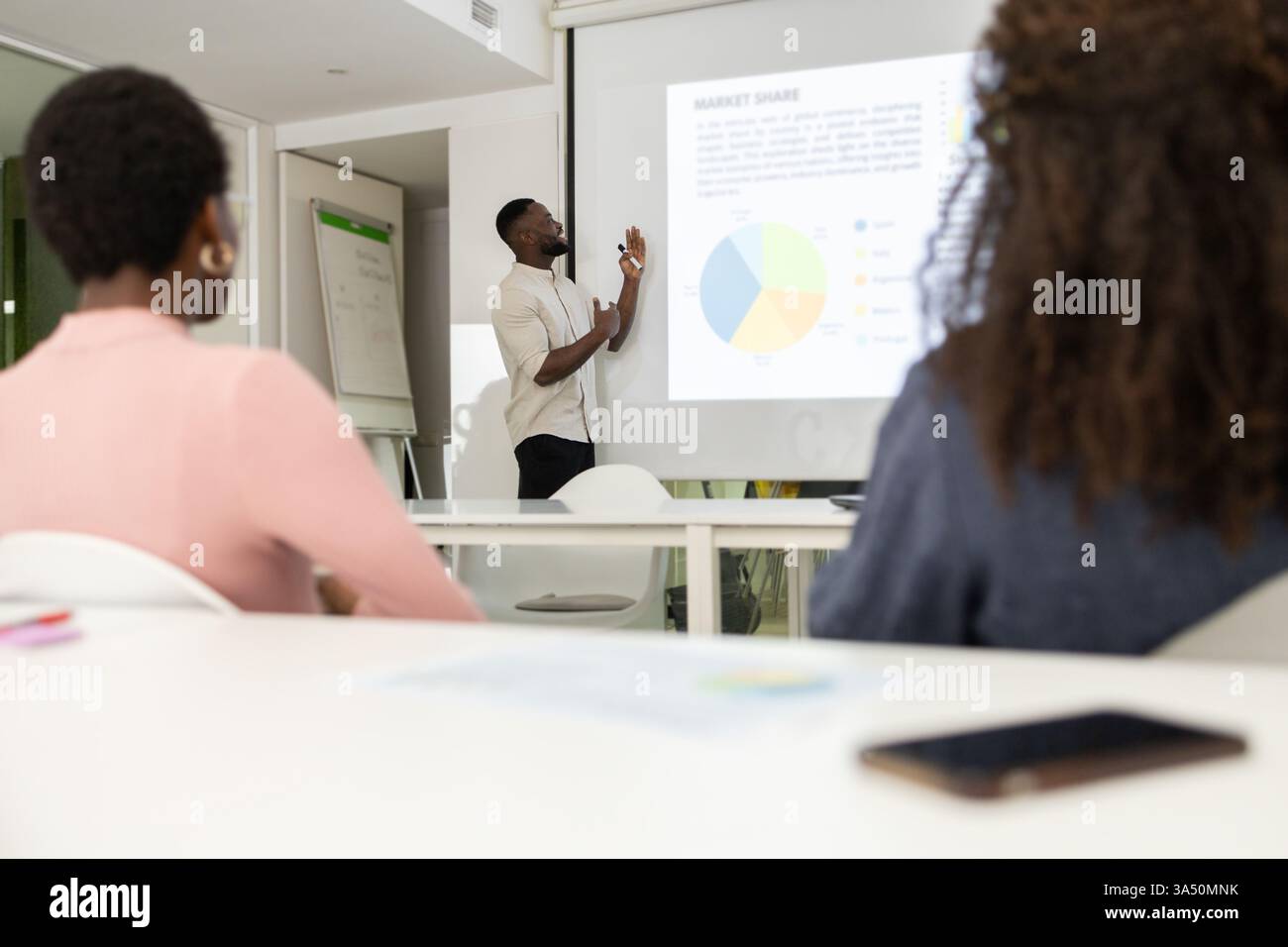 Black man präsentiert Marktanteilsdaten in einem Geschäftstreffen einem vielfältigen Team. Ein starkes Firmenimage für Analytics-, Führungs- und Teamwork-Themen. Geeignet für professionelle Präsentationen und Geschäftskampagnen. Stockfoto
