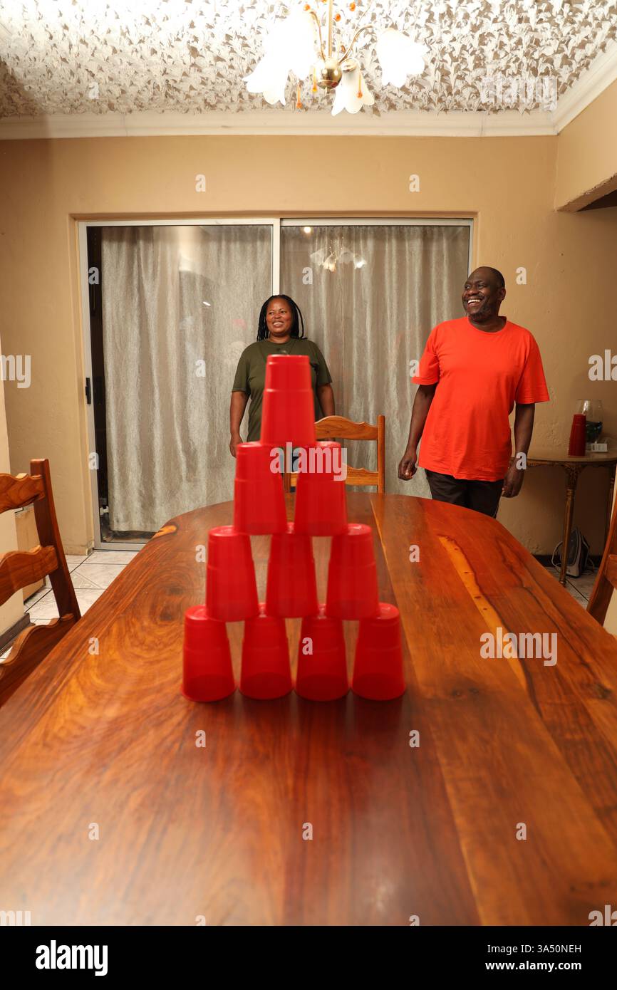 Schwarzes Paar, das ein Cup-Spiel in einem Speisesaal zu Hause spielt. Ein verspielter Lifestyle-Moment, ideal für Home Entertainment und Familienkampagnen. Stockfoto