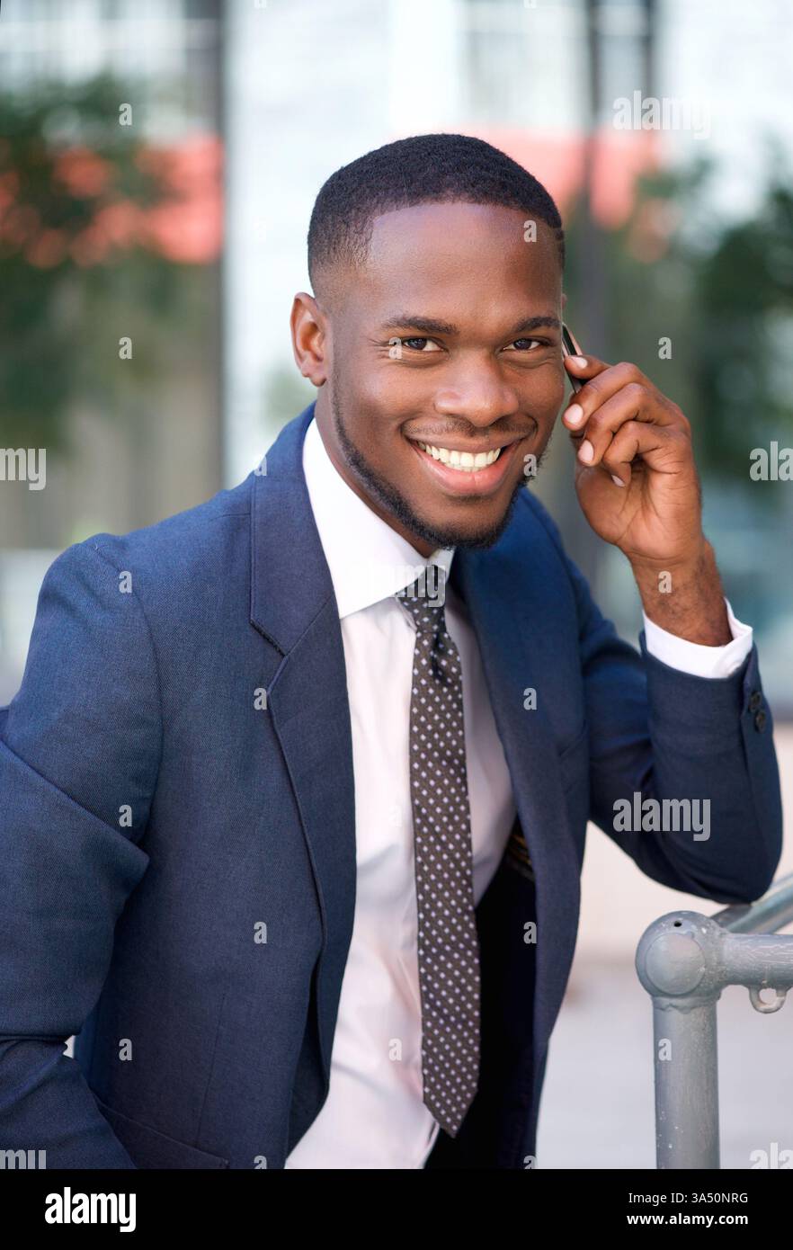 Nahaufnahme eines selbstbewussten jungen nigerianischen Geschäftsmannes, der ein Handy anruft. Der Corporate Vibe passt zu Geschäfts-, Networking- und unternehmerischen Merkmalen. Ein geschliffenes Image für professionelle Profile und Themen der mobilen Kommunikation. Stockfoto
