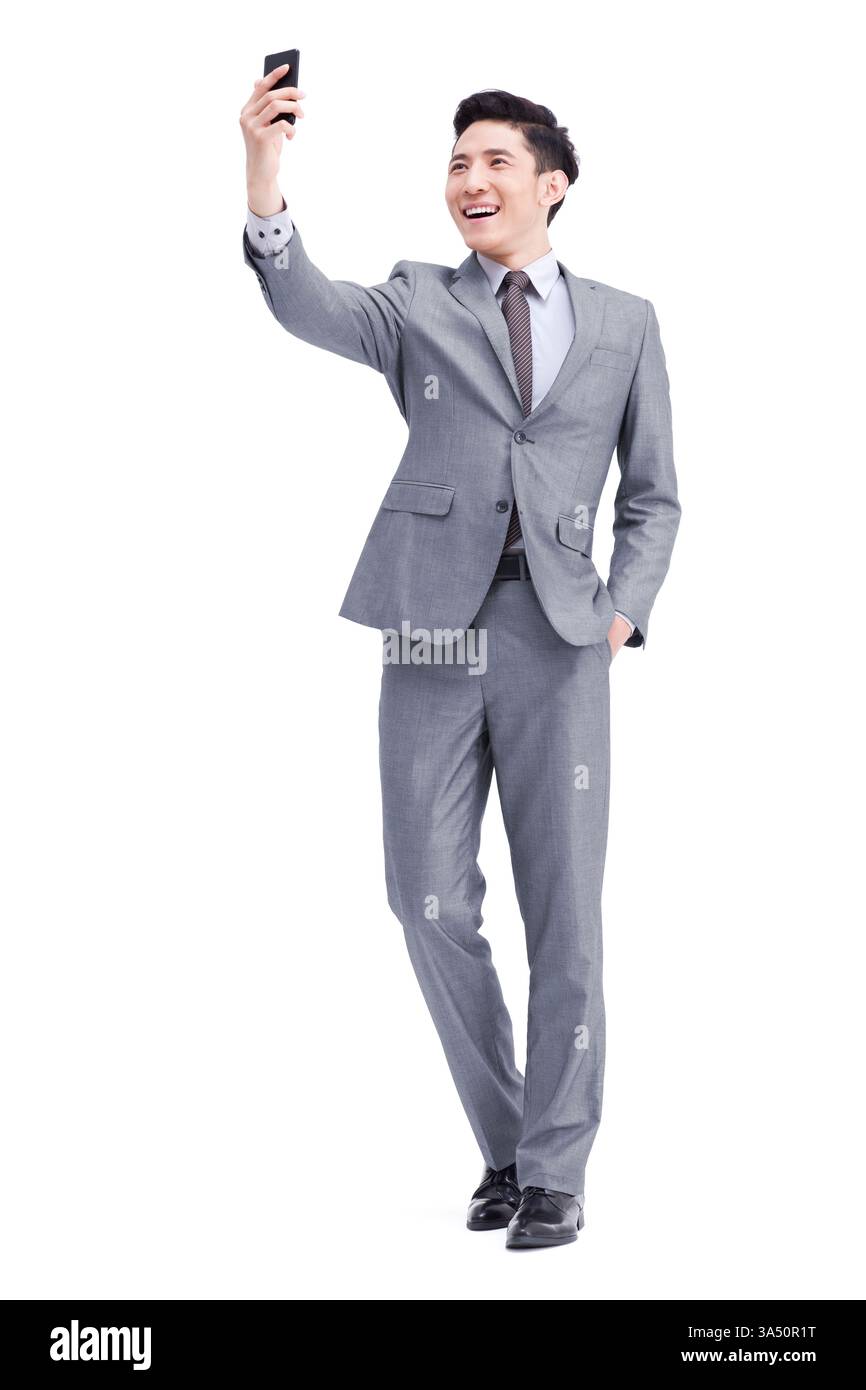 Junger chinesischer Geschäftsmann im Anzug posiert mit einem Handy in einem Studio-Porträt. Dieses technisch versierte Unternehmensimage eignet sich für Technologie, Kommunikation und Corporate Branding mit Kopierbereich. Stockfoto