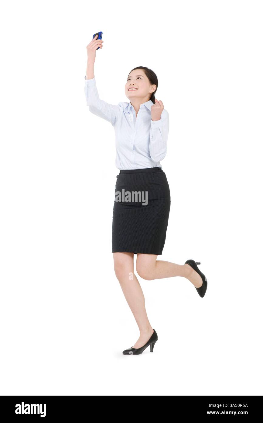 Lächelnde chinesische Geschäftsfrau, die ein Smartphone hält und ein selbstbewusstes, professionelles Porträt präsentiert. Ideal für Unternehmenskommunikation, Mobiltechnologie und Geschäftsthemen in Asien. Ideal für Inhalte über Frauen im Unternehmen, digitale Geräte und Produktivität. Stockfoto