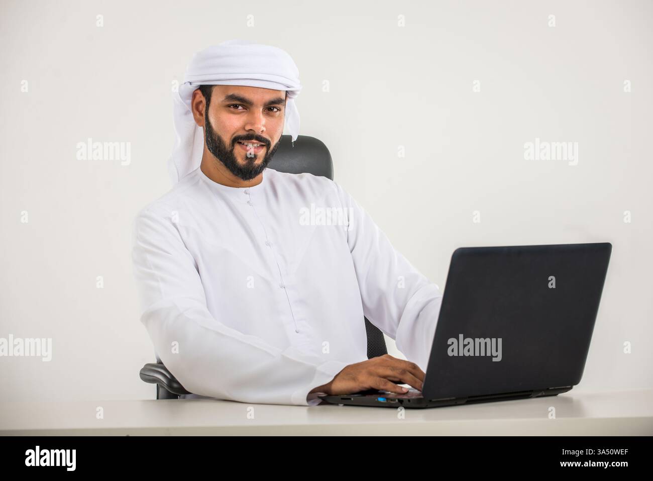 Porträt eines Mannes aus dem Nahen Osten in traditioneller Kandura, der in einem Fotostudio posiert. Die Studioeinrichtung hebt kulturelle Kleidung und modernen Lifestyle hervor. Ideal für Mode-, Identitäts- und Lifestyle-Kampagnen im Nahen Osten. Stockfoto