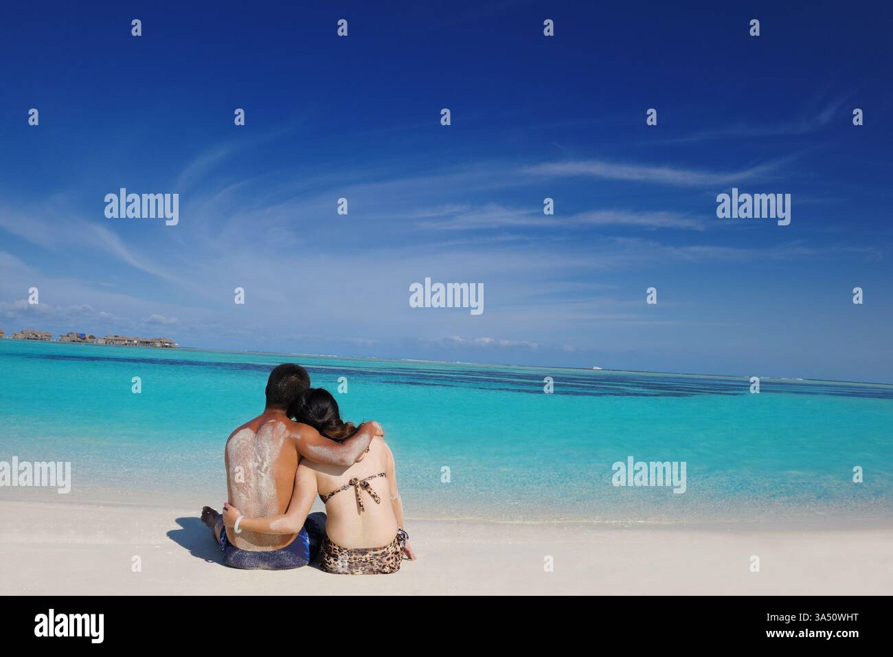 Ein glückliches junges asiatisches Paar genießt einen romantischen Sommertag an einem weißen Sandstrand auf den Malediven. Diese Szene passt zu Reisen, Romantik und Fluchtkampagnen. Perfekt für Badeurlaube, Strandfotografie und Lifestyle-Angebote für Paare. Stockfoto