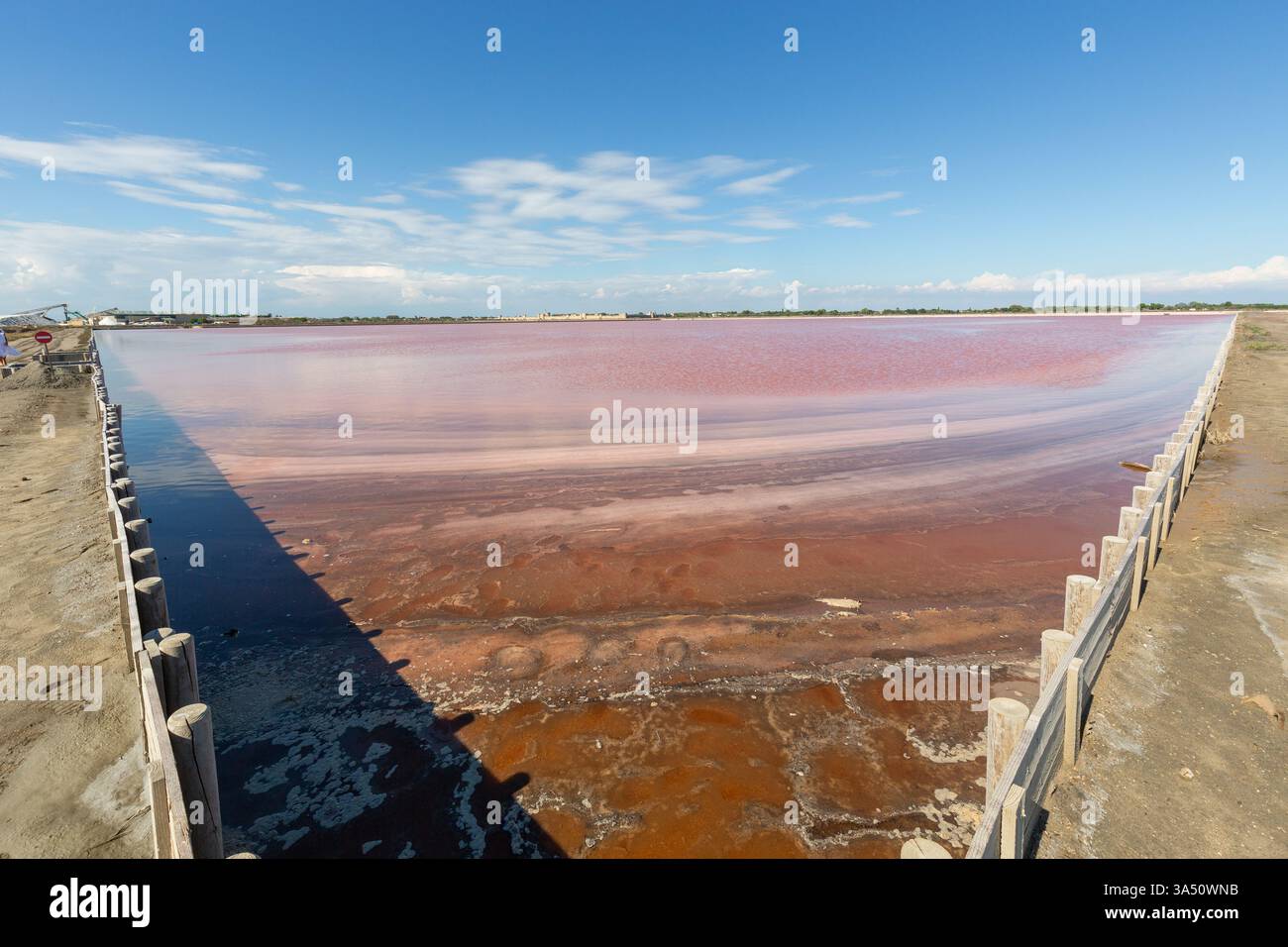 An der Ecke eines Verdunstungsbeckens des Salins du Midi in Aigues-Mortes beginnt die rote Salzlake zu kristallisieren Stockfoto
