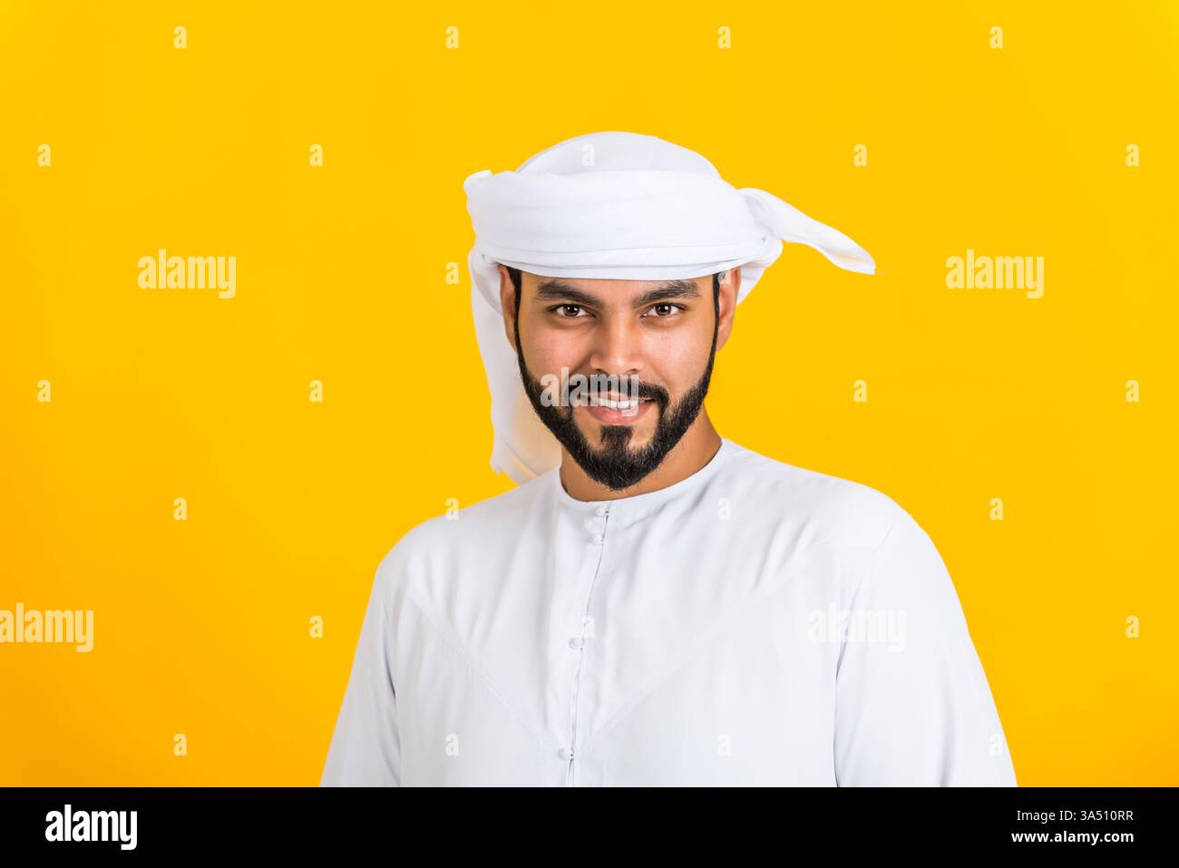 Porträt eines Mannes aus dem Nahen Osten in traditioneller Emirat-Kandura, der in einem Atelier posiert. Dieses konzeptfreundliche Bild verkörpert Lebensstil, Glück und Familienwerte mit einer warmen, authentischen Atmosphäre. Geeignet für kulturelle Branding-, Lifestyle- und Porträtfotografie-Projekte im Nahen Osten. Stockfoto