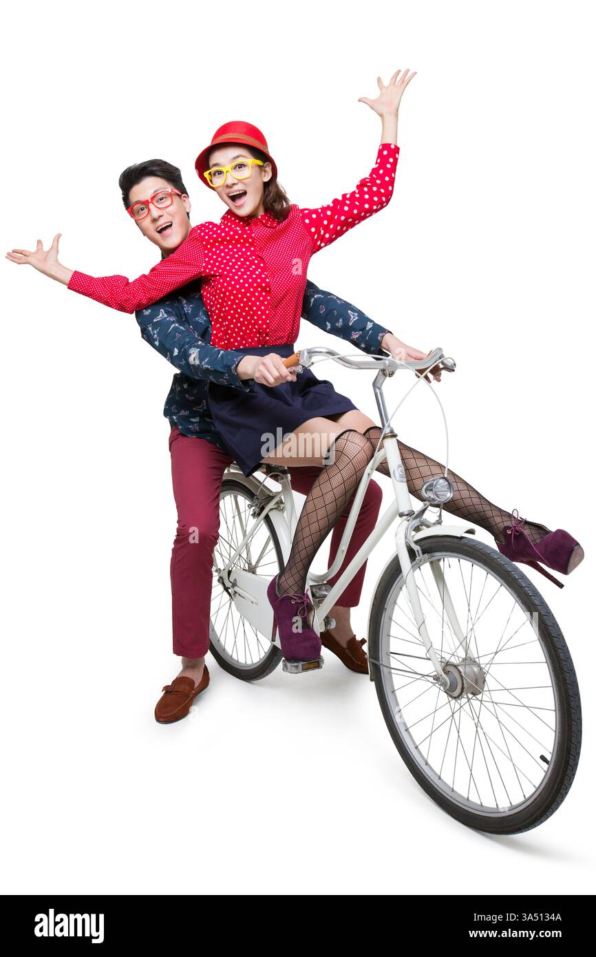 Fröhliches, junges chinesisches Paar, das zusammen Fahrrad fährt. Ein lebendiges Lifestyle-Bild, das Freude und Zweisamkeit vermittelt. Perfekt für Reisen, Dating und städtische Lifestyle-Projekte. Stockfoto