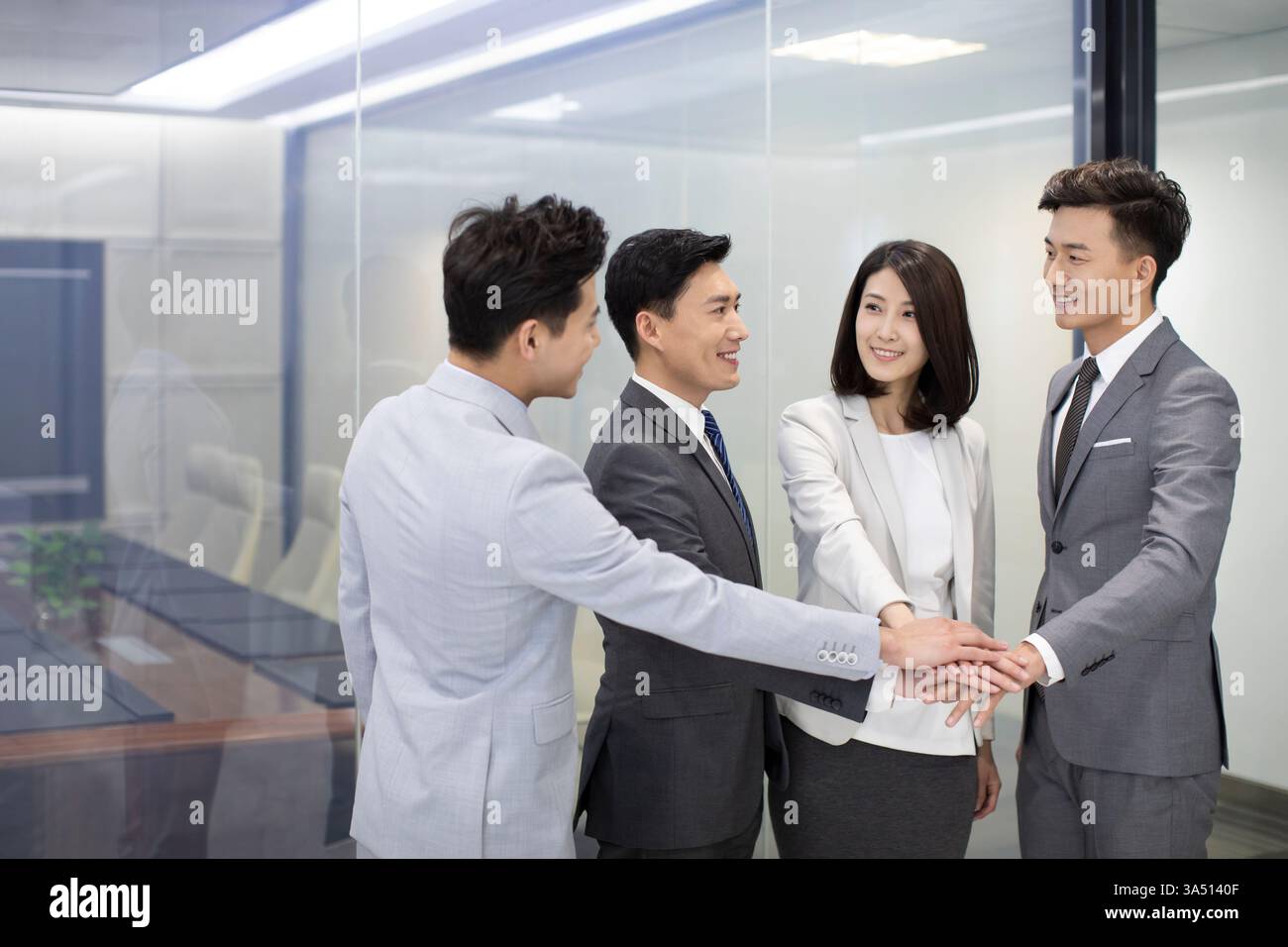 Das chinesische Business-Team legt im Büro in einer Geste der Einheit die Hände zusammen. Dies vermittelt Teamarbeit, Zusammenarbeit und positive Unternehmenskultur. Ideal für Unternehmenskommunikation, Führungsqualitäten und Teamerfolge. Stockfoto