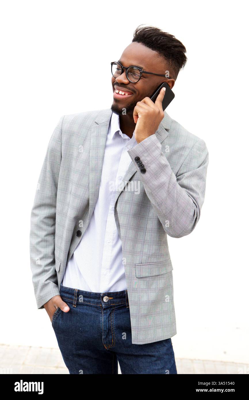 Lächelnder Schwarzer auf einem sauberen weißen Hintergrund, stehend und redet auf seinem Handy. Ideal für Unternehmen, Kommunikation und Mobiltechnologie. Der Kopierbereich für Schlagzeilen oder Branding macht ihn vielseitig für Marketingkampagnen. Stockfoto