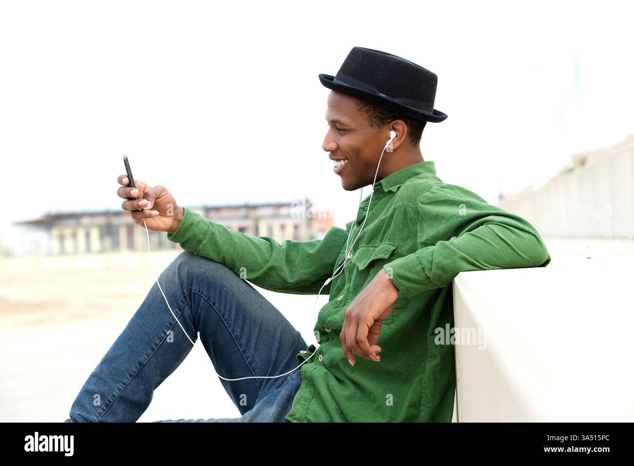 Entspannter Mann, der mit einem MP3-Player Musik im Freien genießt, aufgenommen in einem ungezwungenen, natürlichen Moment. Ein zeitgenössisches Lifestyle-Image, das sich gut für Unterhaltung, Technologie oder Freizeitthemen eignet. Stockfoto