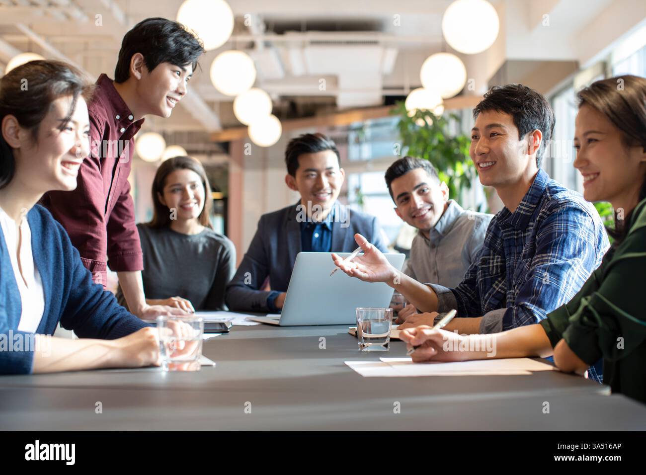 Verschiedene Gruppen von Geschäftsleuten, die sich am Tisch im Büro miteinander unterhalten Stockfoto