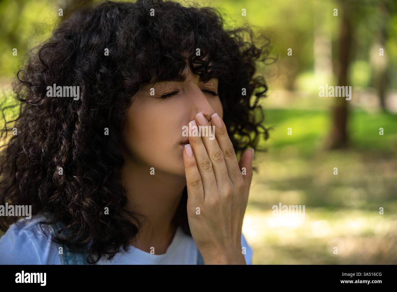 Lockige Mischrasse-Frau mit Symptomen einer saisonalen Allergie und Niesen Stockfoto