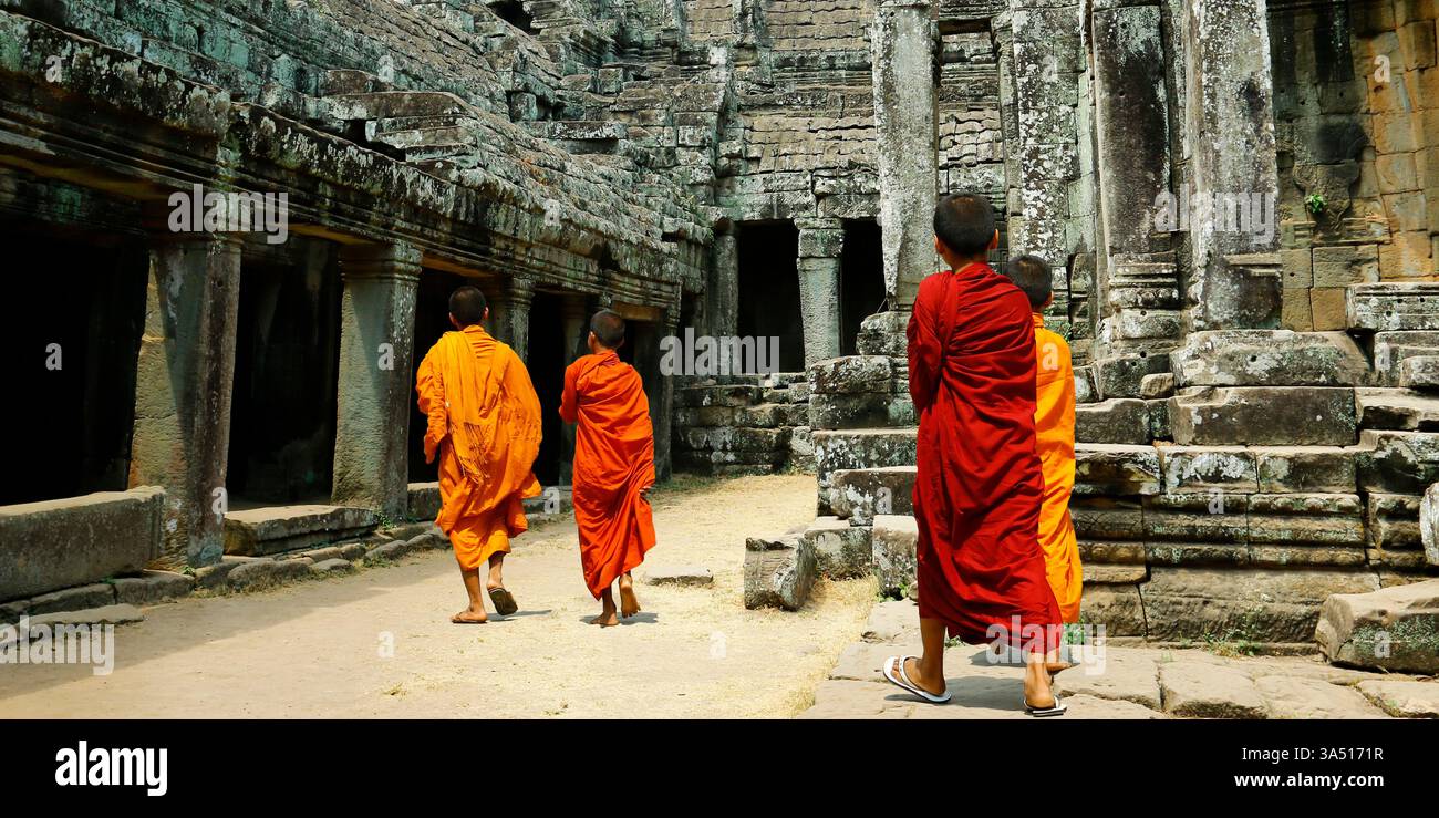 Eine Gruppe asiatischer Mönche in orangefarbenen Gewändern spaziert tagsüber in der Nähe eines Tempels. Es sind keine Gesichter sichtbar, was die Privatsphäre bewahrt und gleichzeitig die buddhistische Kultur und das Tempelleben zeigt. Ein überzeugendes Bild für Reisen, Religion oder Kulturerbe. Stockfoto