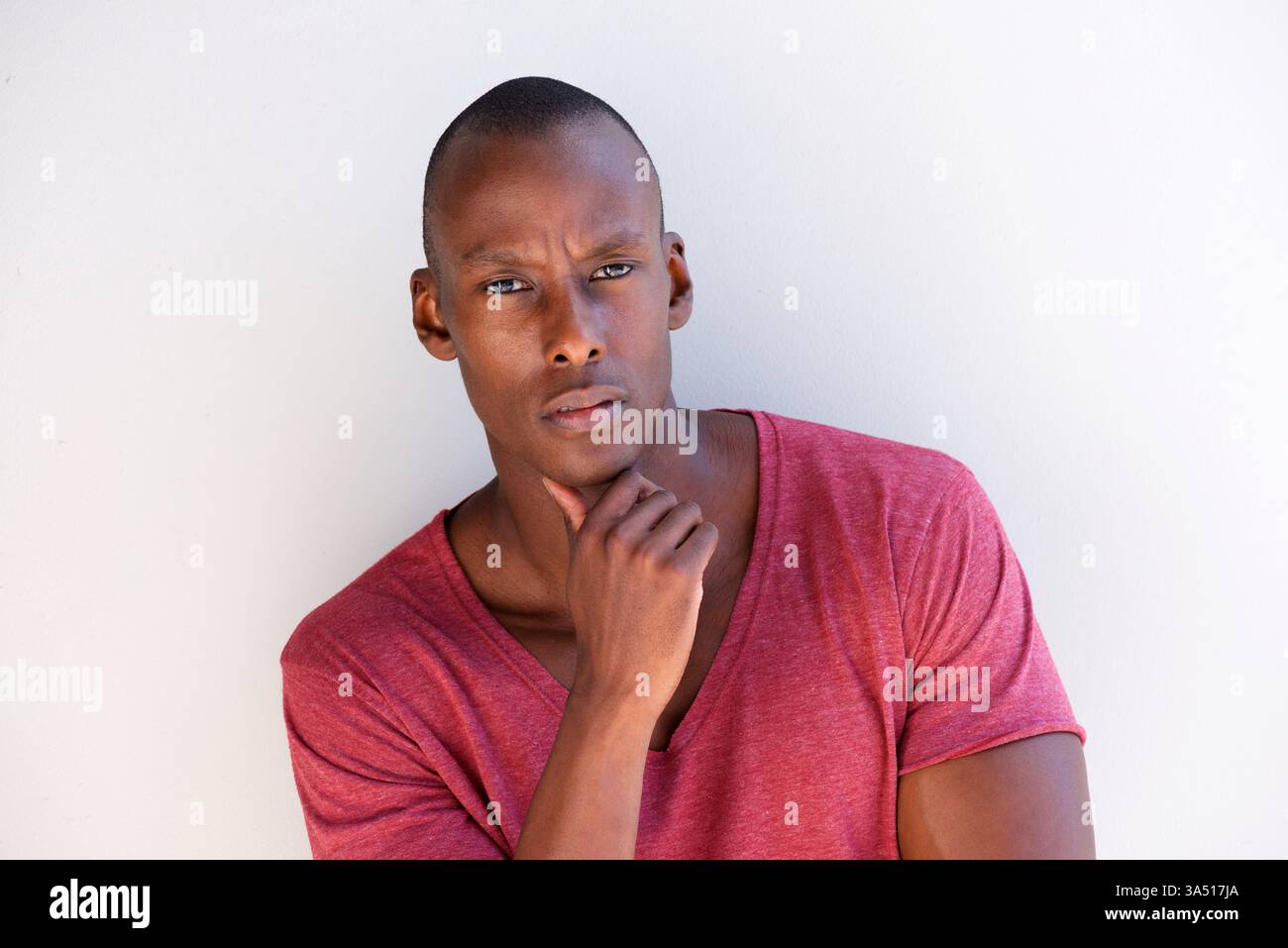 Porträt eines hübschen Schwarzen Mannes mit einem ernsten, kontemplativen Ausdruck vor einem schlichten Hintergrund. Ideal für Unternehmen, Führungskräfte oder redaktionelle Zwecke mit Kopierbereich. Stockfoto