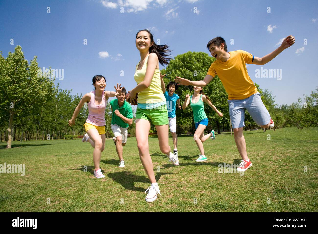 Eine Gruppe chinesischer Freunde, die im Park American Football spielen. Ein lebendiger, energiegeladener Jugendsport-Moment, der zu Teamaktivitäten, Freundschaften und Sportkampagnen am Wochenende passt. Ideal für Sport, Schule oder Campus. Stockfoto