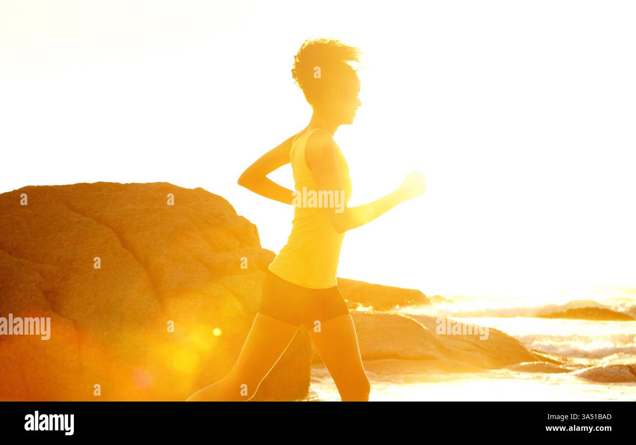 Schwarze Frau mit Afro, die bei Sonnenuntergang am Strand entlang läuft. Ein aktives Lifestyle-Bild mit Bewegung und Küstenlandschaft. Geeignet für Sport, Fitness und Sommerkampagnen. Stockfoto