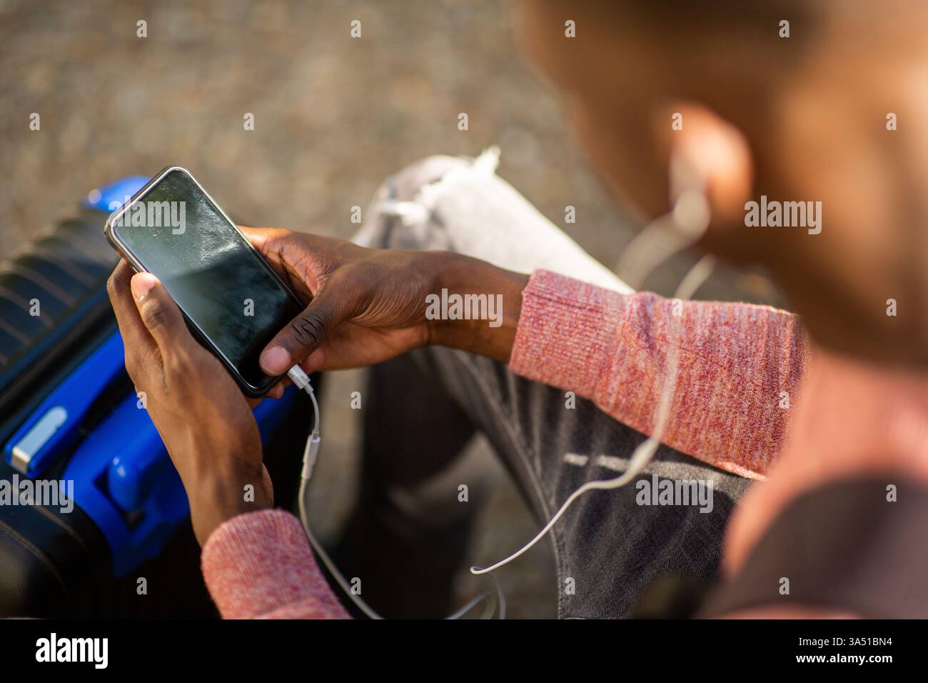 Nahaufnahme eines Schwarzen Mannes, der Kopfhörer trägt, ein Mobiltelefon hält und Musik hört. Geeignet für Technik, mobile Geräte und Musik-Lifestyle-Grafiken. Ideal für Werbung mit Kopfhörern oder schnurloser Technologie. Stockfoto