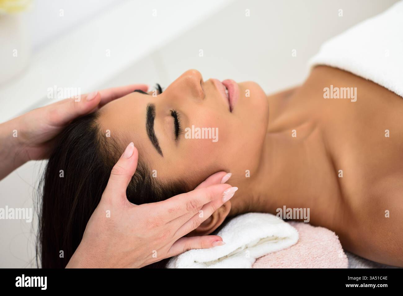 Junge Frau aus dem Nahen Osten erhält Kopfmassage im Spa-Wellnesscenter. Schönheit und ästhetische Konzepte. Stockfoto