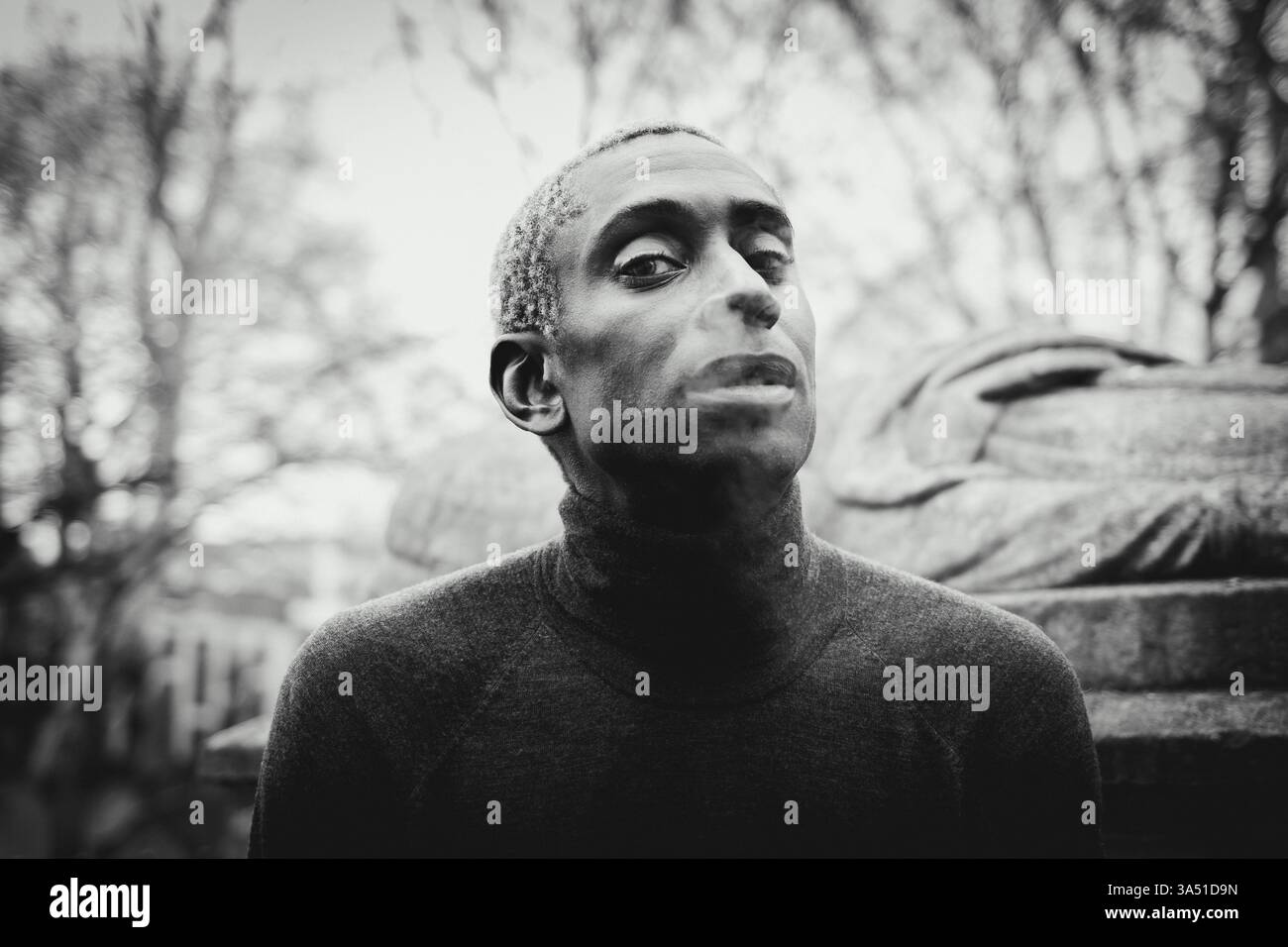 Schwarzer Mann raucht auf einer Straße in einer städtischen Umgebung. Der lässige, besinnliche Moment fängt einen coolen, alltäglichen Lebensstil ein. Stockfoto