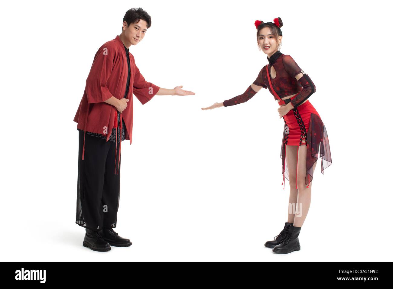 Fröhliches, junges chinesisches Paar begrüßt sich in einem Studio-Setting. Der lebendige Moment passt zu Lifestyle- und Festthemen mit modernem Stil. Stockfoto