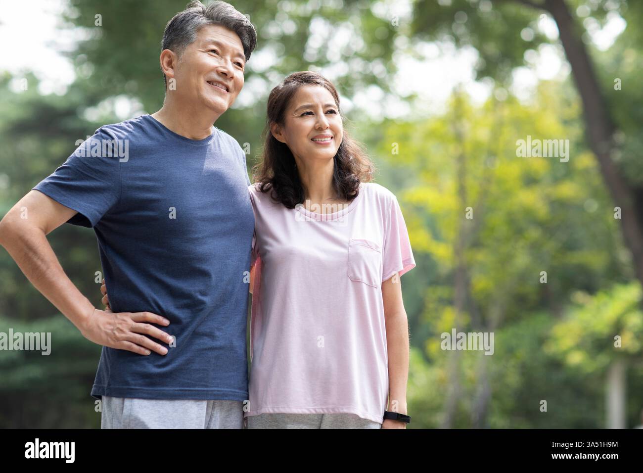 Lächelndes chinesisches Seniorenpaar, das tagsüber im Park steht Stockfoto