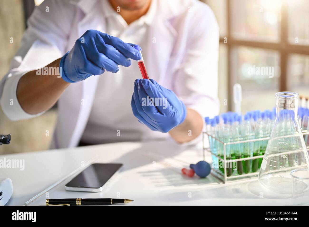 Fachwissenschaftler in einem forensisch-wissenschaftlichen Labor, das Serumprobenuntersuchungen durchführt. Eine zugeschnittene Aufnahme hebt Laborausrüstung und analytische Arbeit in einer Kriminaluntersuchung oder im biotechnologischen Kontext hervor. Ideal für Arbeitsabläufe in Wissenschaft, Forschung und Labor. Stockfoto