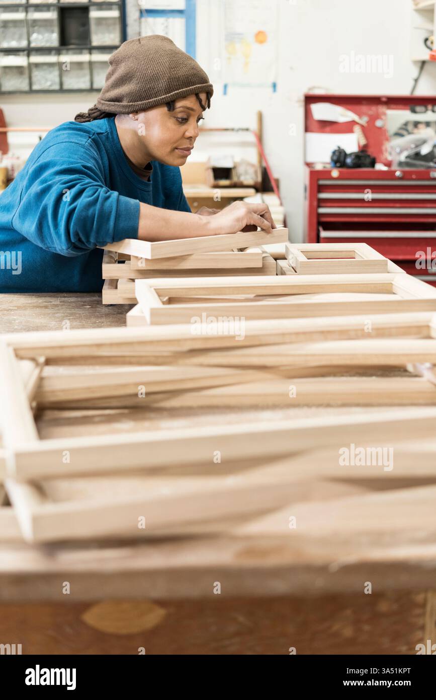 Schwarze Zimmerfrau, die sich darauf konzentrierte, einen Schrank in einer Holzwerkstatt zu bauen. Eine starke Vertretung von Frauen im Fachhandel, in Handwerkskunst und in der Stärkung der Arbeitskraft. Stockfoto
