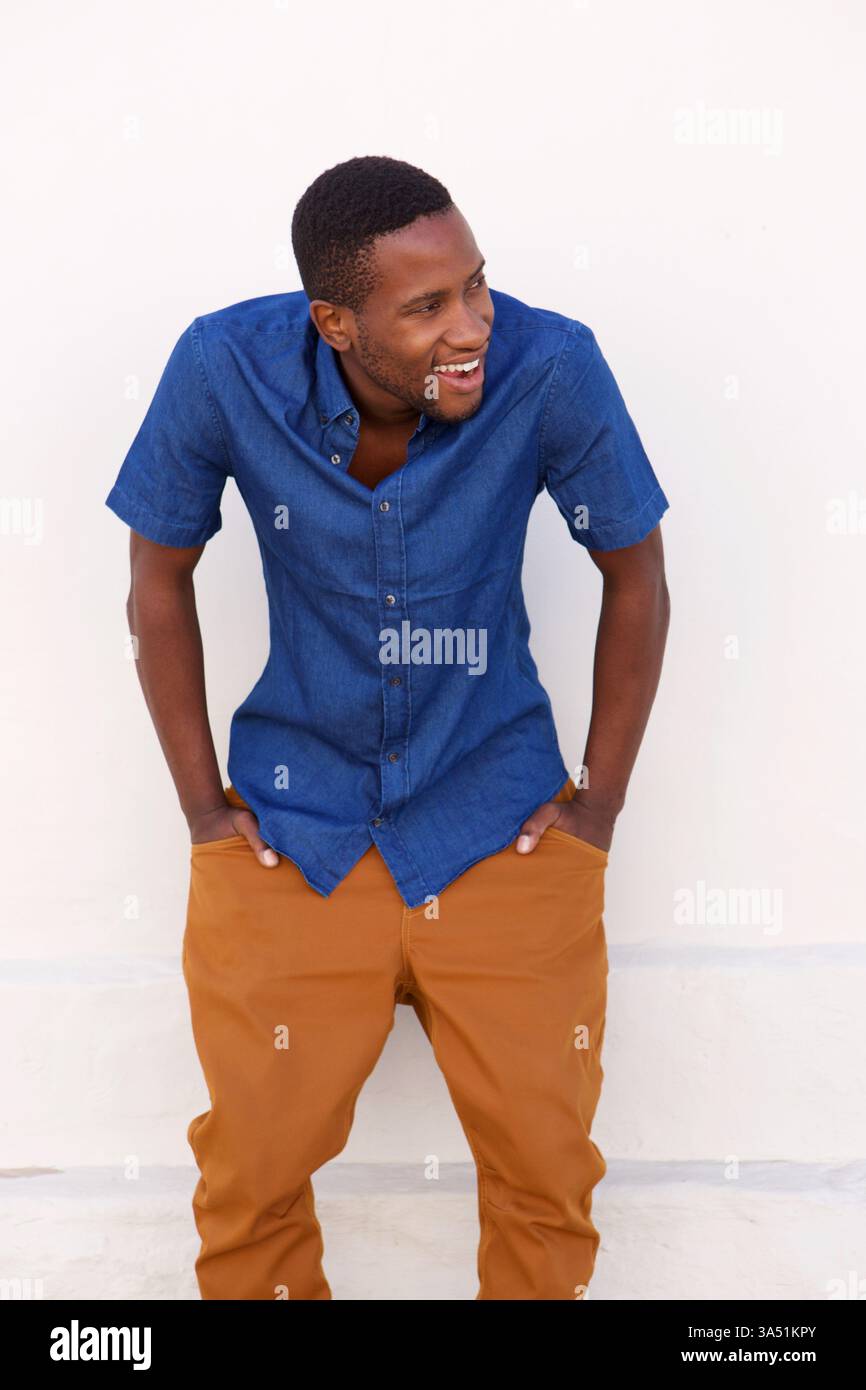 Porträt eines coolen, stilvollen jungen Afrikaners, der mit einem Lächeln wegschaut. Vielseitig einsetzbar für Lifestyle, Mode und positives Branding in urbanen Kontexten. Stockfoto