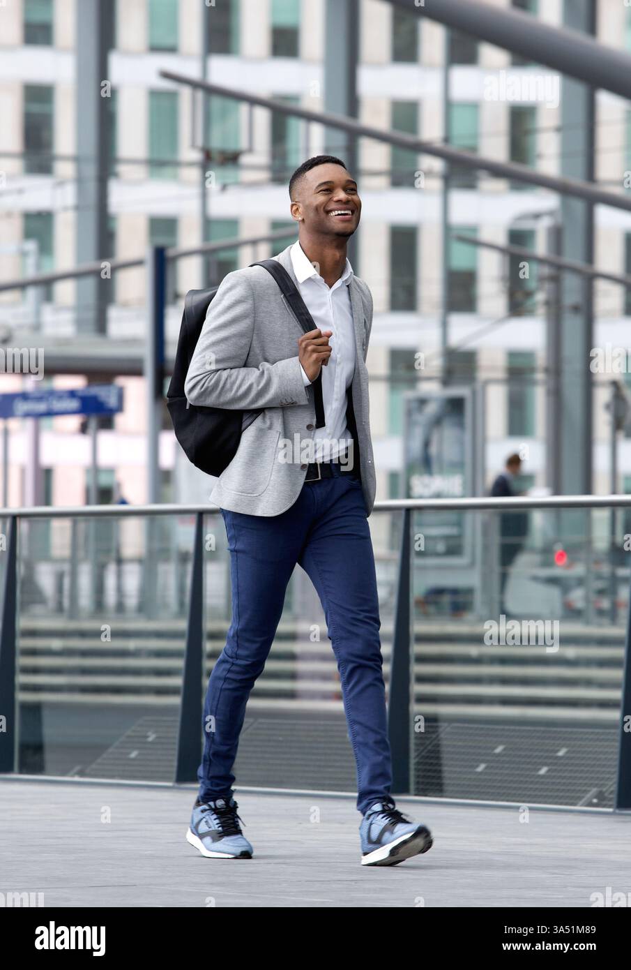 Porträt eines schicken Mannes, der mit einer Tasche auf einer Station läuft. Eine moderne Pendleratmosphäre mit lässiger Mode, geeignet für Lifestyle, Reisen und urbane Werbung. Stockfoto