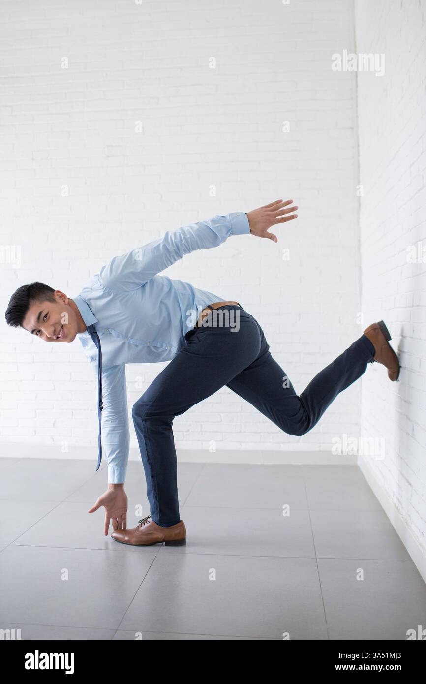 Lächelnder chinesischer Geschäftsmann, der eine Dehnungsübung an seinem Schreibtisch macht. Der Moment vermittelt Fitness, Wohlbefinden und einen ausgewogenen Unternehmensstil. Stockfoto