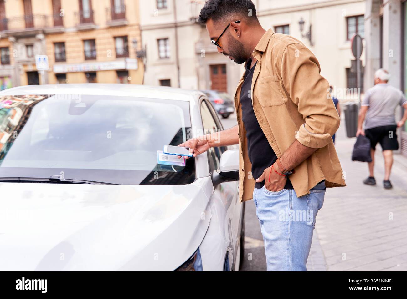 Urban man nutzt eine mobile App, um ein Auto zu mieten, indem er einen QR-Code in einer Stadt scannt. Ideal für Carsharing, Mobilität, Technologie und On-Demand-Transportkampagnen. Die Szene legt Wert auf Komfort und digitale Lösungen im modernen urbanen Leben. Stockfoto