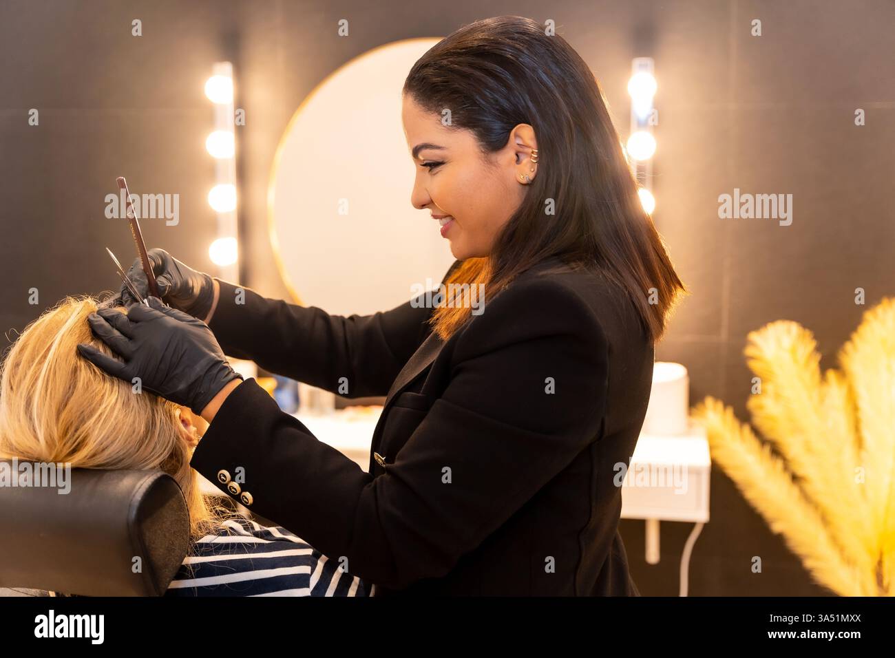 Nahaufnahme einer spanischsprachigen Kosmetikerin, die in einem modernen Salon Augenbrauen formt. Diese Schönheitsbehandlungsszene ist ideal für Kosmetik-, Hautpflege- und Salondienstleistungen. Stockfoto