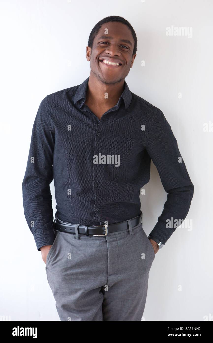 Porträt eines gutaussehenden afroamerikanischen Geschäftsmannes, der an einer weißen Wand lächelt. Perfekt für Unternehmenskommunikation, Führungsqualitäten und professionelle Services. Stockfoto