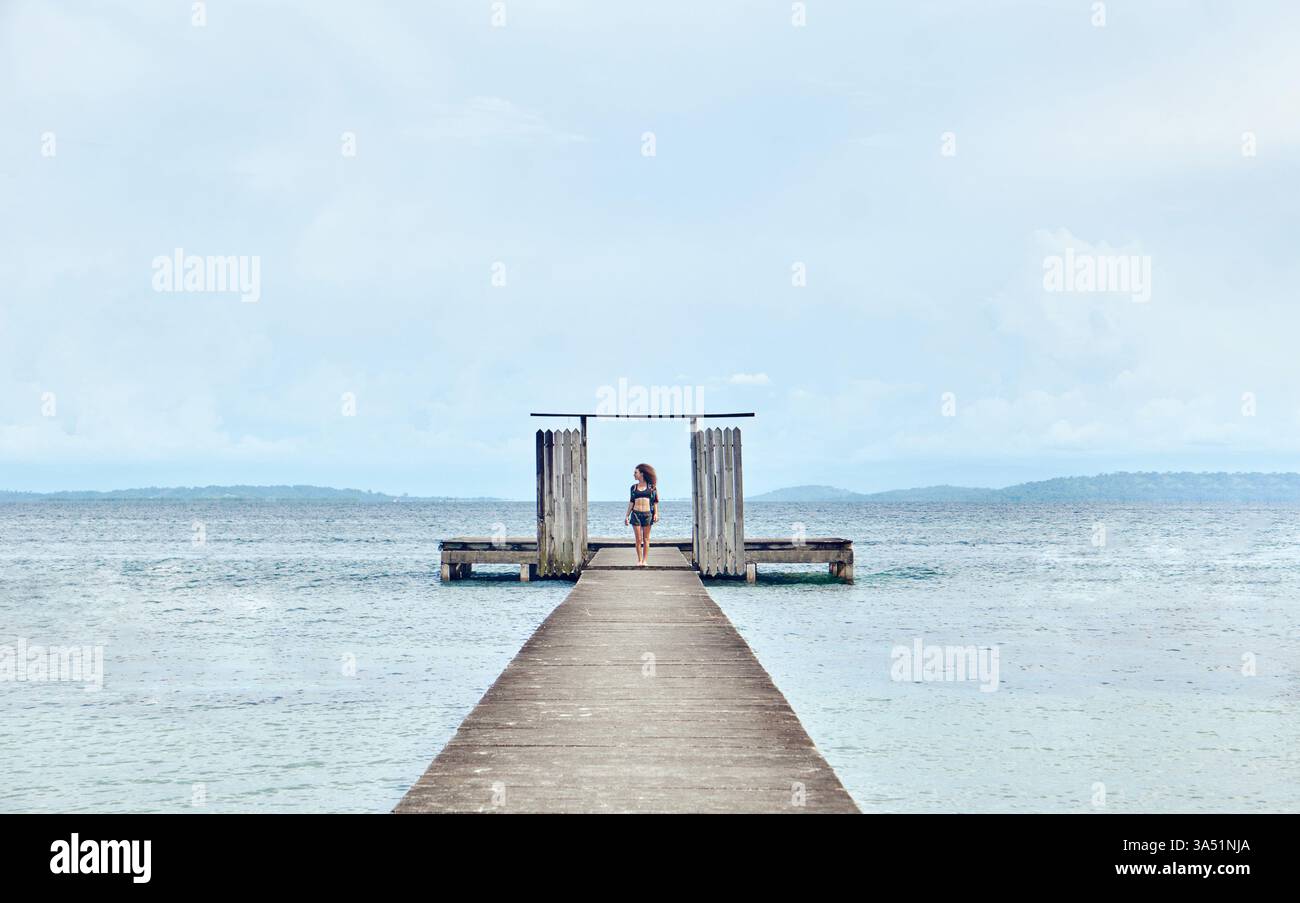 Hispanische Frau, die tagsüber auf einem Holzsteg am Strand steht Stockfoto