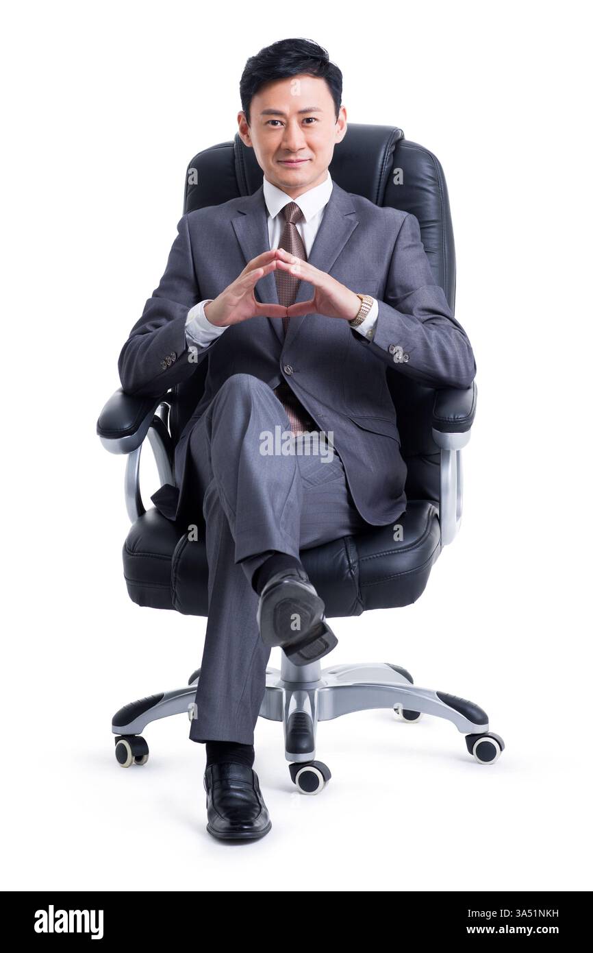 Ein reifer chinesischer Manager sitzt in einem modernen Büro auf einem Stuhl. Er lächelt und schaut in die Kamera, projiziert Selbstvertrauen und Führungsstärke. Perfekt für Führungskräfte, Unternehmensprofile und professionelle Grafikfunktionen mit Kopierbereich. Stockfoto