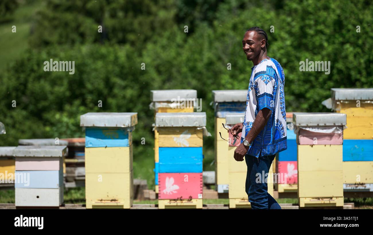 Porträt eines Schwarzen Imkers auf einer Honigfarm, der die lokale Imkerei und Honigproduktion zeigt. Die Szene vermittelt Unternehmertum und nachhaltige Landwirtschaft mit Bienen und Bienenstöcken. Stockfoto
