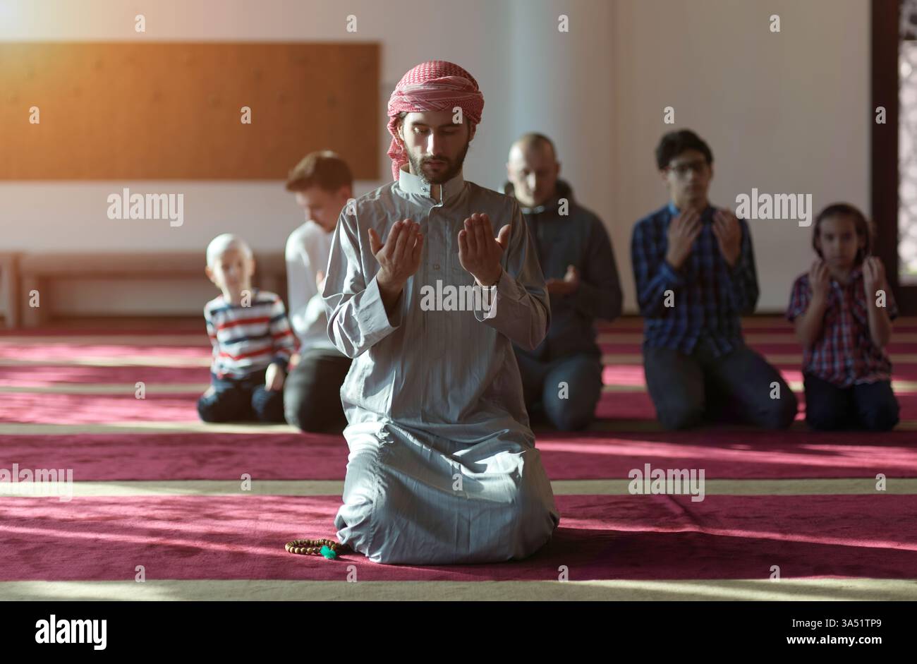Eine Gruppe von Anbetern betet namaz in einer Moschee und fängt einen Moment der Hingabe ein. Die Szene zeigt den Glauben und das gemeinschaftliche Gebet in einem islamischen Umfeld. Geeignet für Ramadan, Moscheekultur und spirituellen Lebensstil. Stockfoto