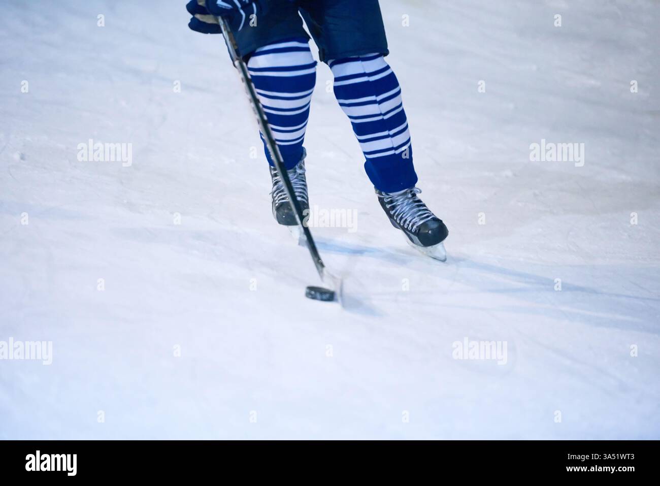 Dynamische Eishockey-Action auf der Eisbahn, mit einem männlichen Spieler in Bewegung. Ein intensiver Moment, der die Sportlichkeit in einem Wintersport einfängt. Ideal für Sport-, Wettkampf- und Teambilder. Stockfoto