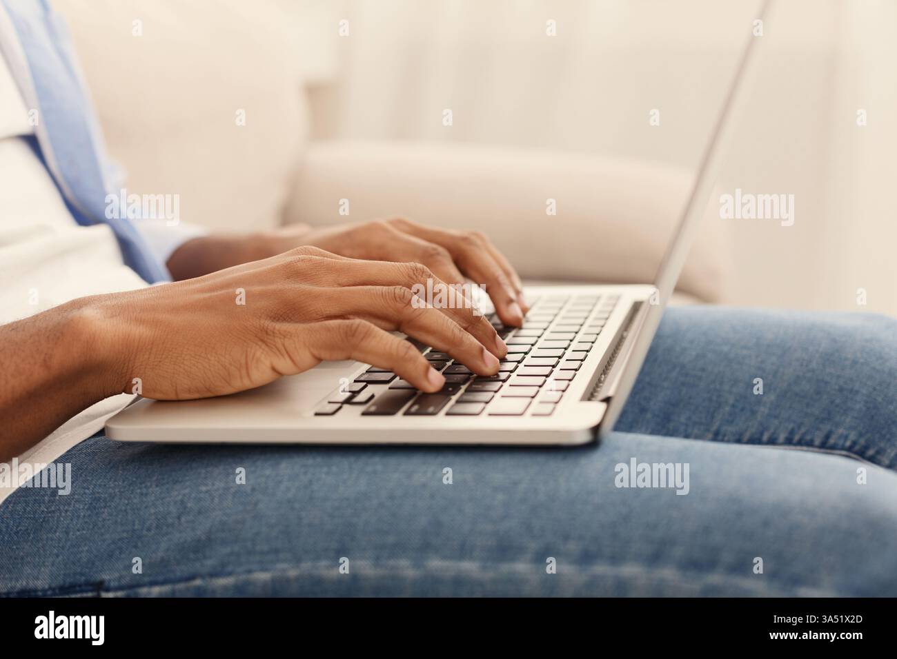 Afroamerikaner sitzt an einem Schreibtisch, Hände auf der Tastatur, während er ein Videospiel auf einem Laptop spielt. Ein modernes Gaming- und Technikthema, das sich für Home Entertainment, E-Sport oder Online-Lernkontexte eignet. Viel Platz zum Kopieren, um Text oder Branding hinzuzufügen. Stockfoto