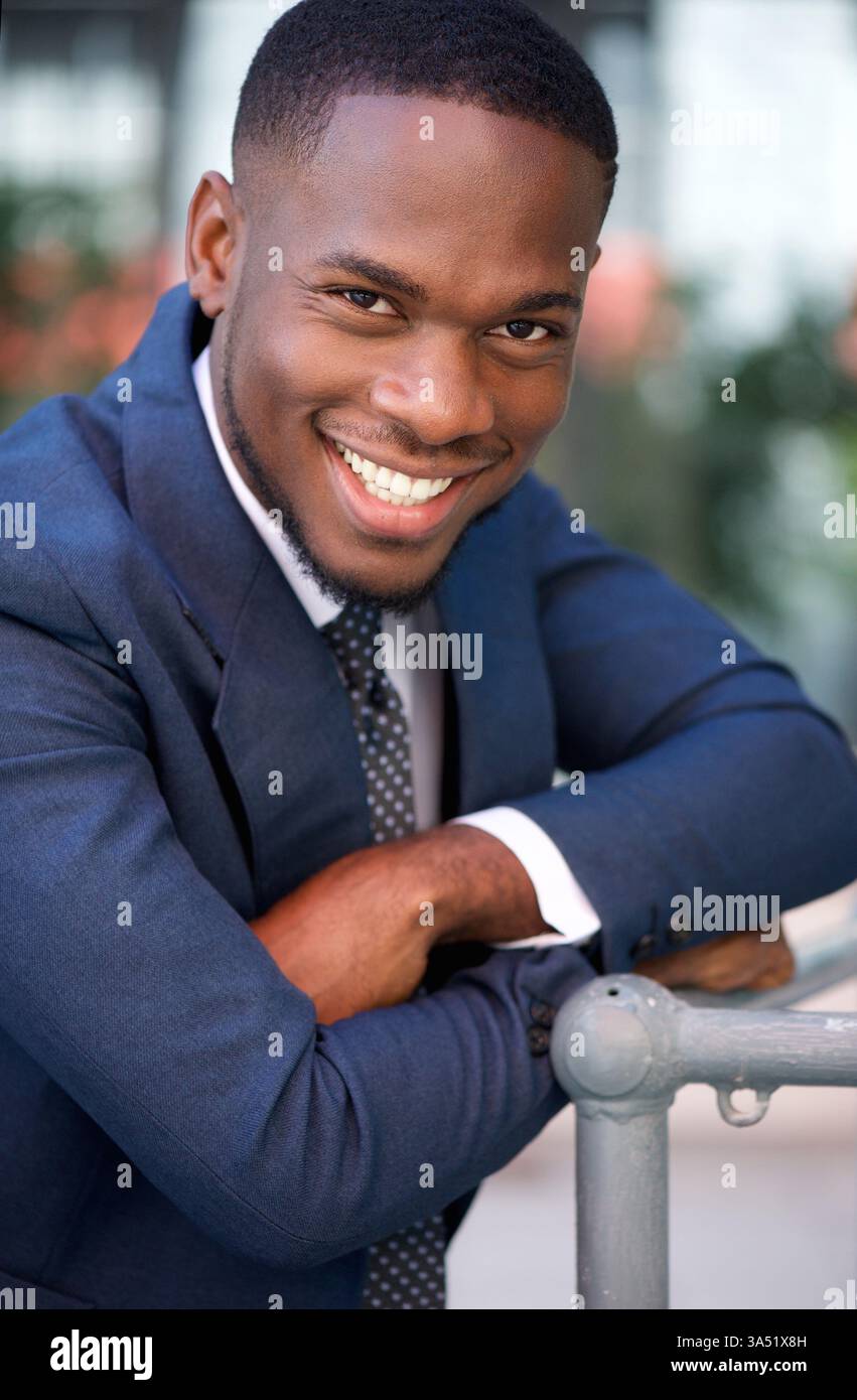 Nahaufnahme Porträt eines selbstbewussten nigerianischen Geschäftsmannes, der mit überkreuzten Armen lächelt. Der polierte Look und der Anzug vermitteln Professionalität und Erfolg. Ideal für Unternehmens- und Führungsprojekte. Stockfoto