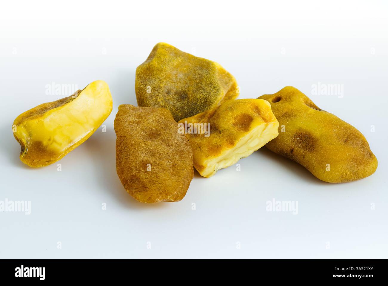 Ein hochwertiges Bild von roher polnischer Baltischen Bernstein auf weiß zeigt seine organische Textur und natürliche Farbvariationen, was es zu einer ausgezeichneten Wahl für Stockfoto