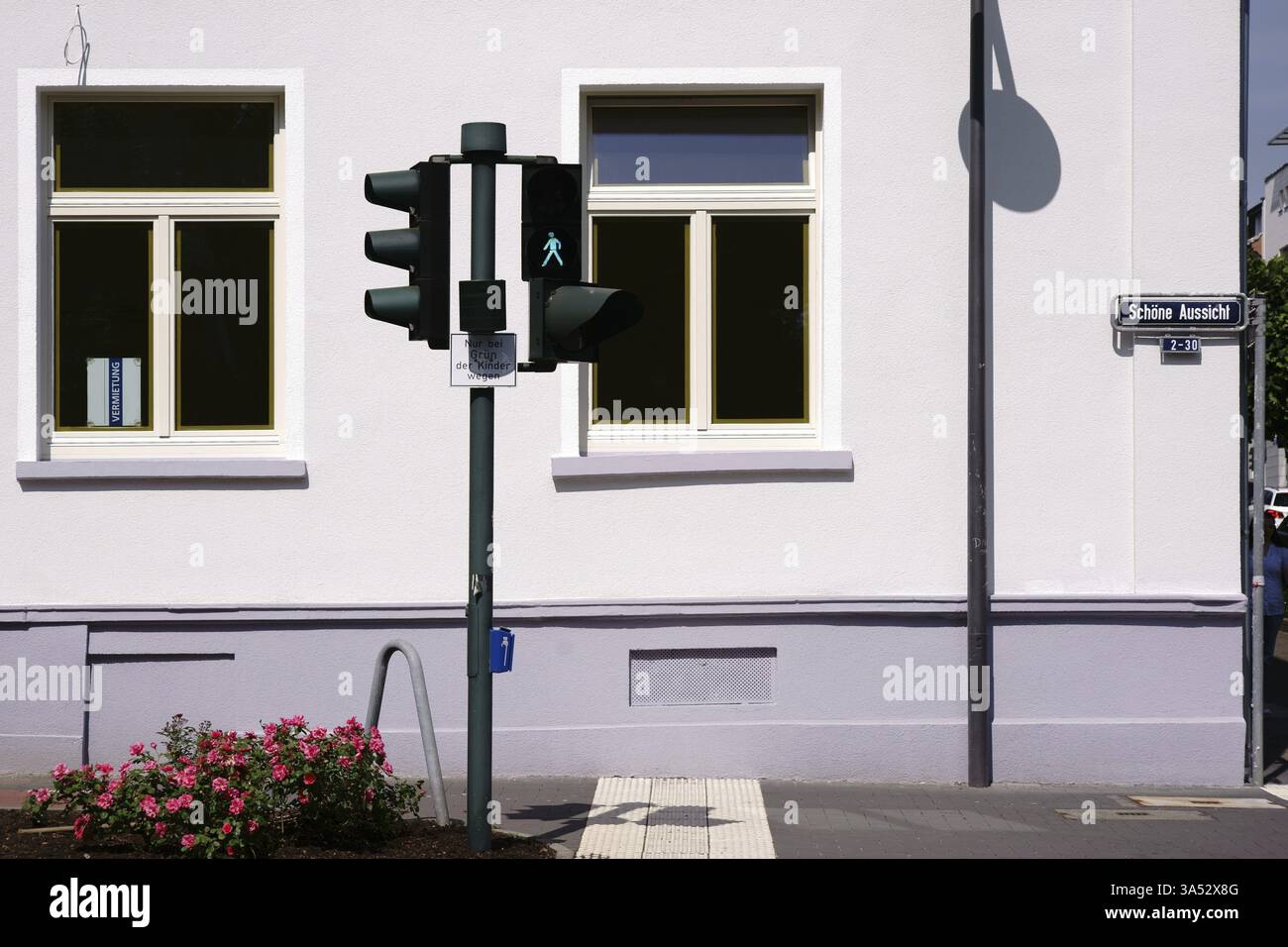 Eine Ampel wirft Schatten auf die helle Fassade eines Wohn- und Geschäftsgebäudes, das vermietet werden kann Stockfoto